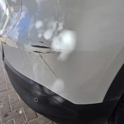 תיעוד נזקי פח, שריטות ומעיכה בפגוש אחורי של רכב פרטי לבן