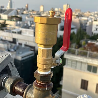 שסתום ומחבר על גג עם נוף עירוני ברקע