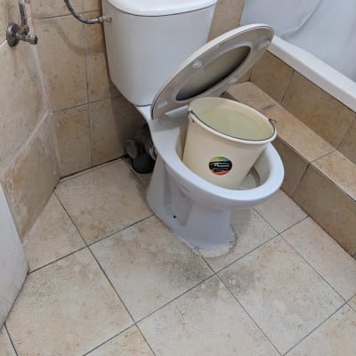 דלי פלסטיק בתוך אסלה בחדר אמבטיה