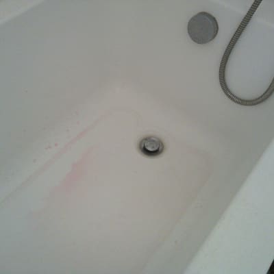 אמבטיה עם כתמי מים ורודים ליד הניקוז