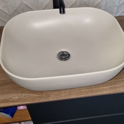 כיור לבן עם ברז שחור על משטח עץ