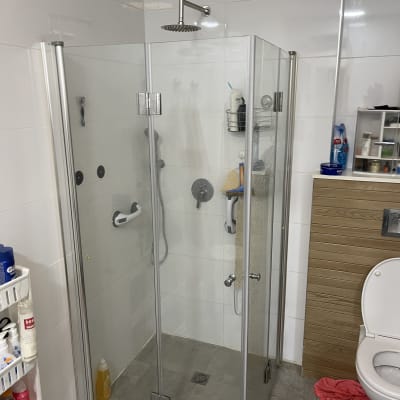 מקלחון זכוכית עם ראש מקלחת ומדף מוצרים