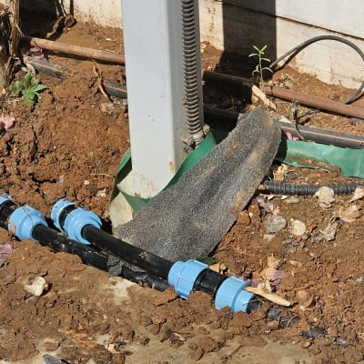 צינור שחור עם מחברים כחולים באדמה חשופה