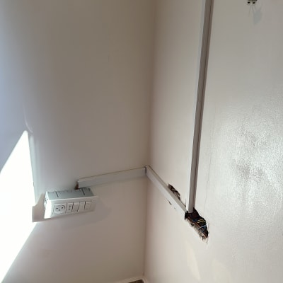 חוטי חשמל חשופים בקיר עם תעלות פלסטיק