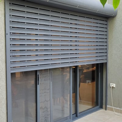 תריסים אפורים סגורים על חלון זכוכית גדול