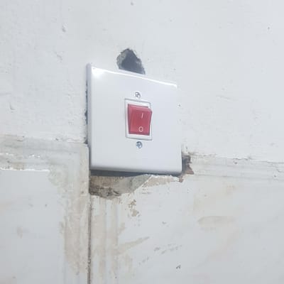 מתג חשמלי מותקן על קיר לבן עם חור לידו