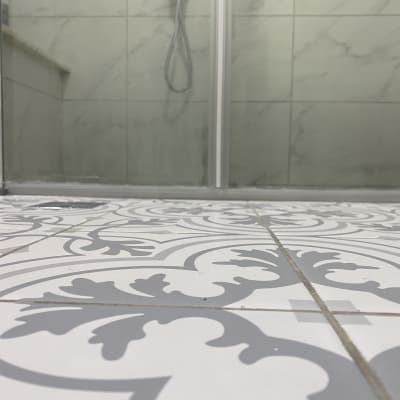 מקלחון עם דלתות זכוכית ורצפת אריחים מעוצבת