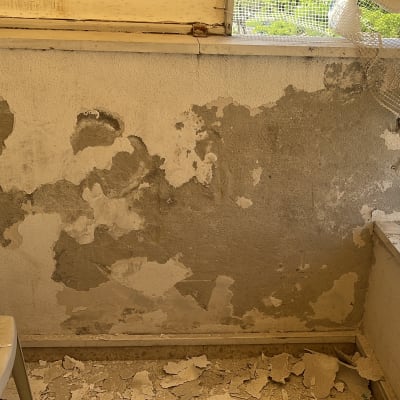 קיר מתקלף עם כיסא פלסטיק ורשת קרועה