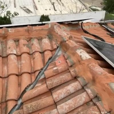 גג רעפים עם לוחות סולאריים ונוף כפרי ברקע