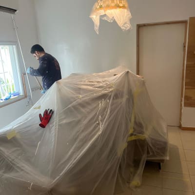 אדם עובד ליד חלון, רהיטים מכוסים בניילון