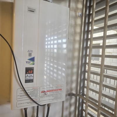 מחמם מים גז מותקן ליד חלון עם צינורות מחוברים