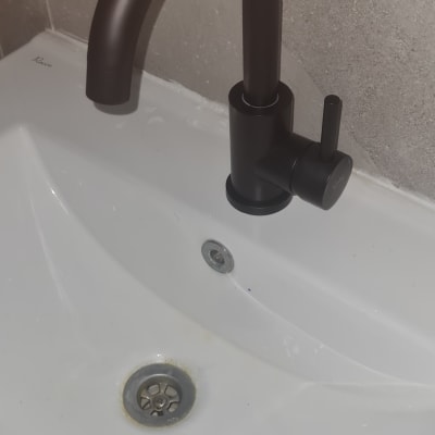 ברז שחור וכיור לבן עם ניקוז