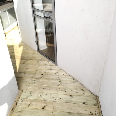 רצפת עץ חדשה ליד דלת זכוכית במרפסת קטנה