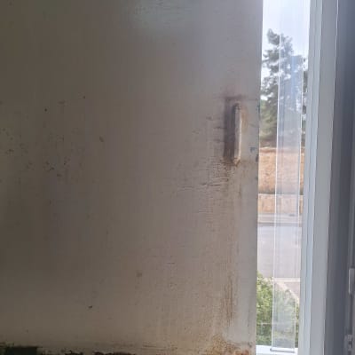 חלון עם סימני רטיבות ועובש על הקיר