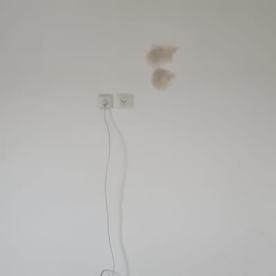 שקע חשמל עם כבל תלוי על קיר לבן