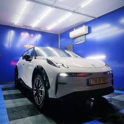 רכב לבן בחדר עם קירות כחולים ותאורה חזקה