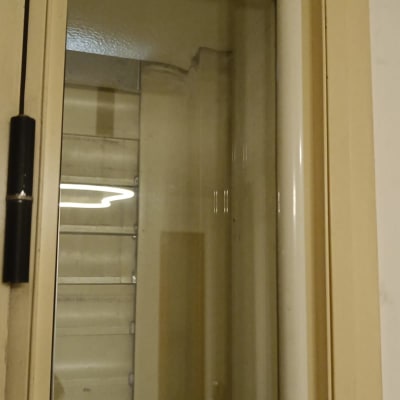 תריסים סגורים מאחורי חלון זכוכית עם מסגרת בהירה