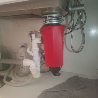 מתקן אדום מתחת לכיור עם צינורות ואביזרי אינסטלציה