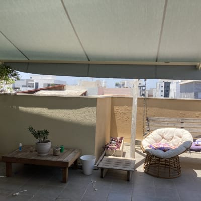סוכך בד מתוח מעל מרפסת עם ריהוט גן