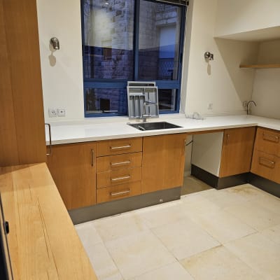 מטבח נקי עם ארונות עץ ומשטח עבודה לבן