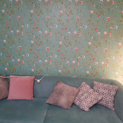 ספה עם כריות מול טפט פרחוני על קיר