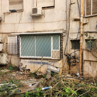 חלון אלומיניום עם סורגים על קיר בניין ישן