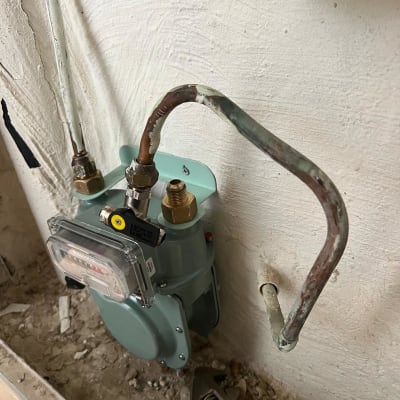 מונה גז מותקן על קיר עם צינורות וכלי עבודה