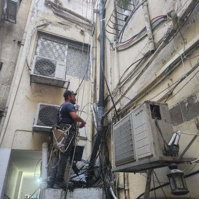 אדם עובד על צינורות חיצוניים בבניין ישן.