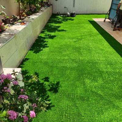 דשא סינטטי עם פרחים ורודים ועובד בגינה