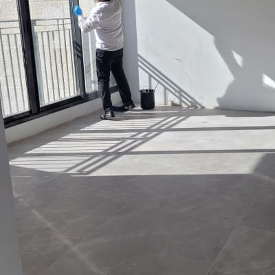 אדם מנקה חלון עם כפפות ודלי