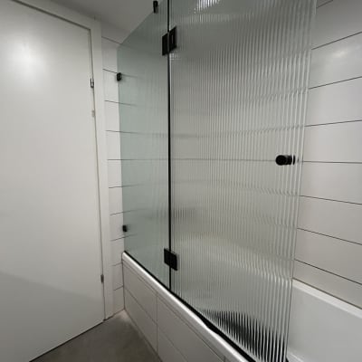 דלת זכוכית מחוספסת במקלחת עם אריחים לבנים