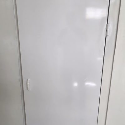 דלת לבנה עם ידית פשוטה על רקע קיר לבן