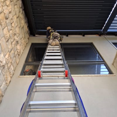 אדם על סולם עובד בגובה ליד חלון