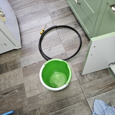 דלי ירוק, צינור שחור ומברג על רצפה