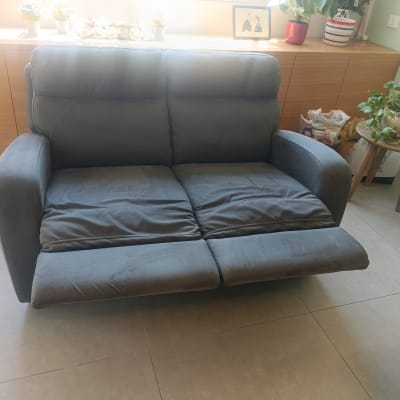 ספה אפורה עם משענת רגליים מורמת בחדר מואר