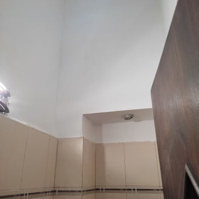 קיר צבוע בלבן עם תקרה גבוהה ומנורה