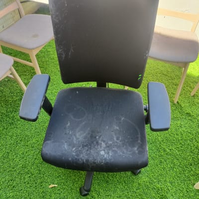כיסא משרדי שחור עם כתמים על דשא ירוק