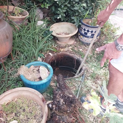 אדם מחזיק מוט ליד פתח ביוב בגינה