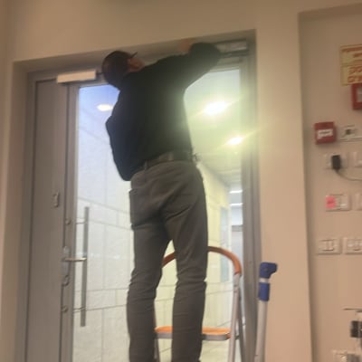 אדם על סולם מתקן מנעול על דלת זכוכית