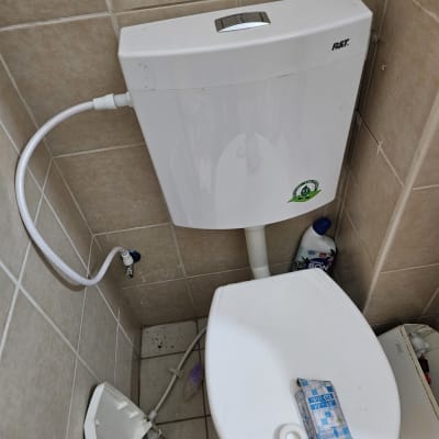 אסלה עם מיכל הדחה וצינור מים מחובר