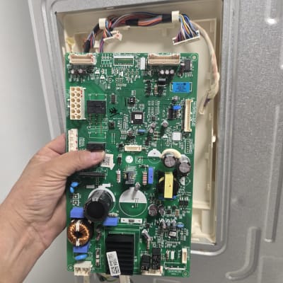 לוח בקרה של מקרר מוחזק ביד ליד חיווטים