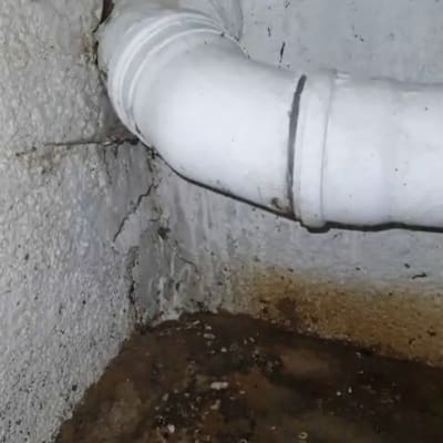 צינור לבן עם נזילה על קיר רטוב