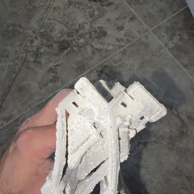 חלקי פלסטיק שבורים עם אבק על רצפה אפורה
