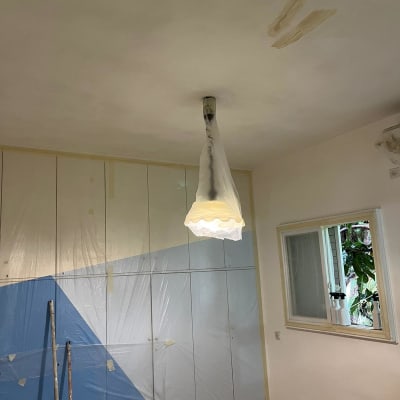 חדר עם תקרה צבועה, ניילון מכסה ארון ומנורה עטופה