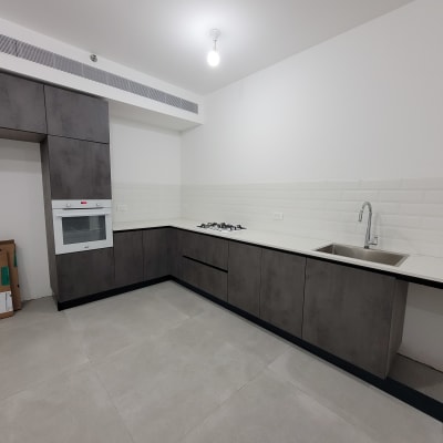 מטבח נקי עם כיור וברז, ארונות אפורים ותנור מובנה