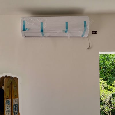 מזגן מותקן על קיר עם סולם ליד חלון פתוח