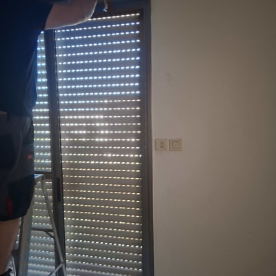 אדם מתקין תריסים בחלון עם סולם