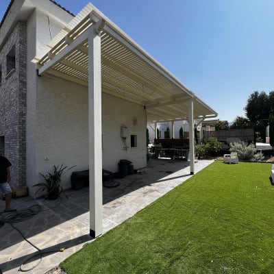 פרגולה לבנה מעל דשא סינתטי בחצר בית