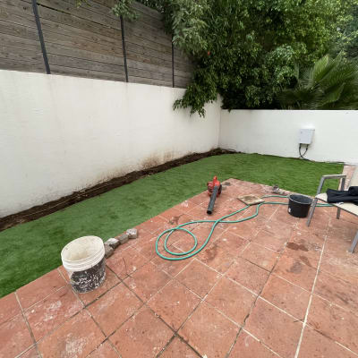 דשא סינתטי, צינור מים, מפוח עלים ודלי בגינה