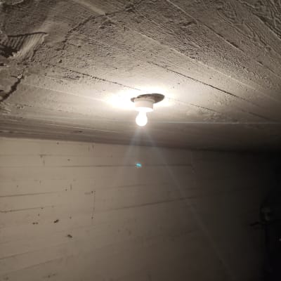 נורה חשמלית דולקת בתקרה לבנה